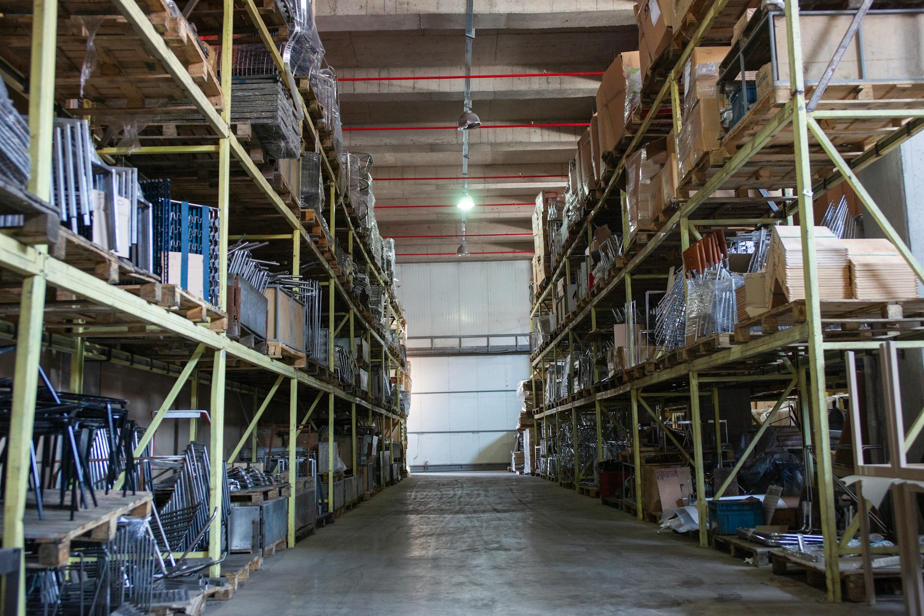 Industrial warehouse aisle with high-bay racking — interior monitoring station placement zone for an AIB- and SQF-compliant IPM program