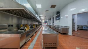 Commercial kitchen floor drain in an Indianapolis restaurant — the primary breeding harborage for drain flies (Psychodidae) where organic biofilm coats the inside walls and pipe trap
